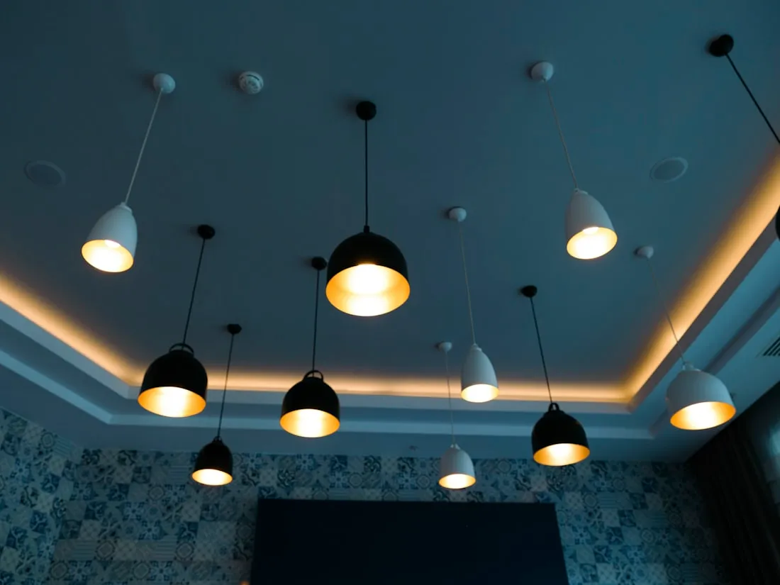 Plafond bleu avec suspensions noires et corniche lumineuse dans une salle de restaurant