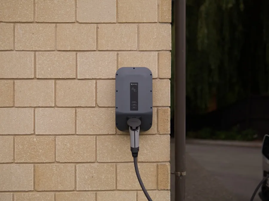 Borne de recharge murale grise fixée sur un mur en brique claire, câble branché