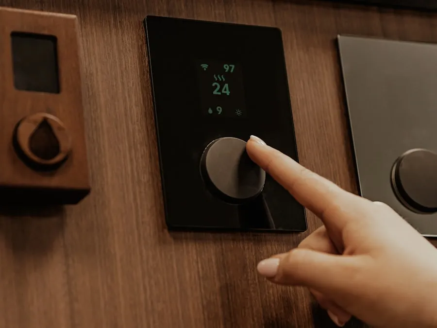 Doigt réglant un thermostat encastré à écran noir sur un mur en bois